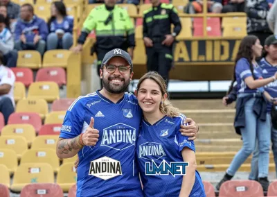 Hombre y mujer visten prendas de Millonarios con logo de Andina